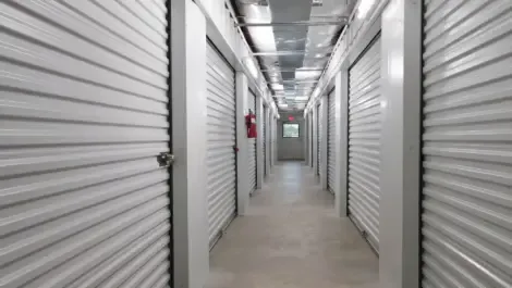 Multiple indoor storage units with roll-up doors along a hallway
