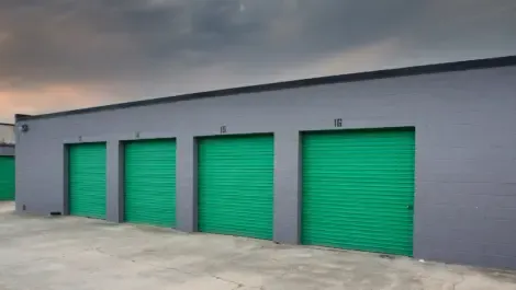 Three closed outdoor storage units with metal roll-up doors