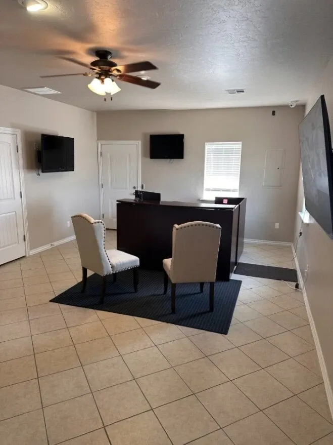 Room with a tile floor and an small desk with chairs below a ceiling fan.