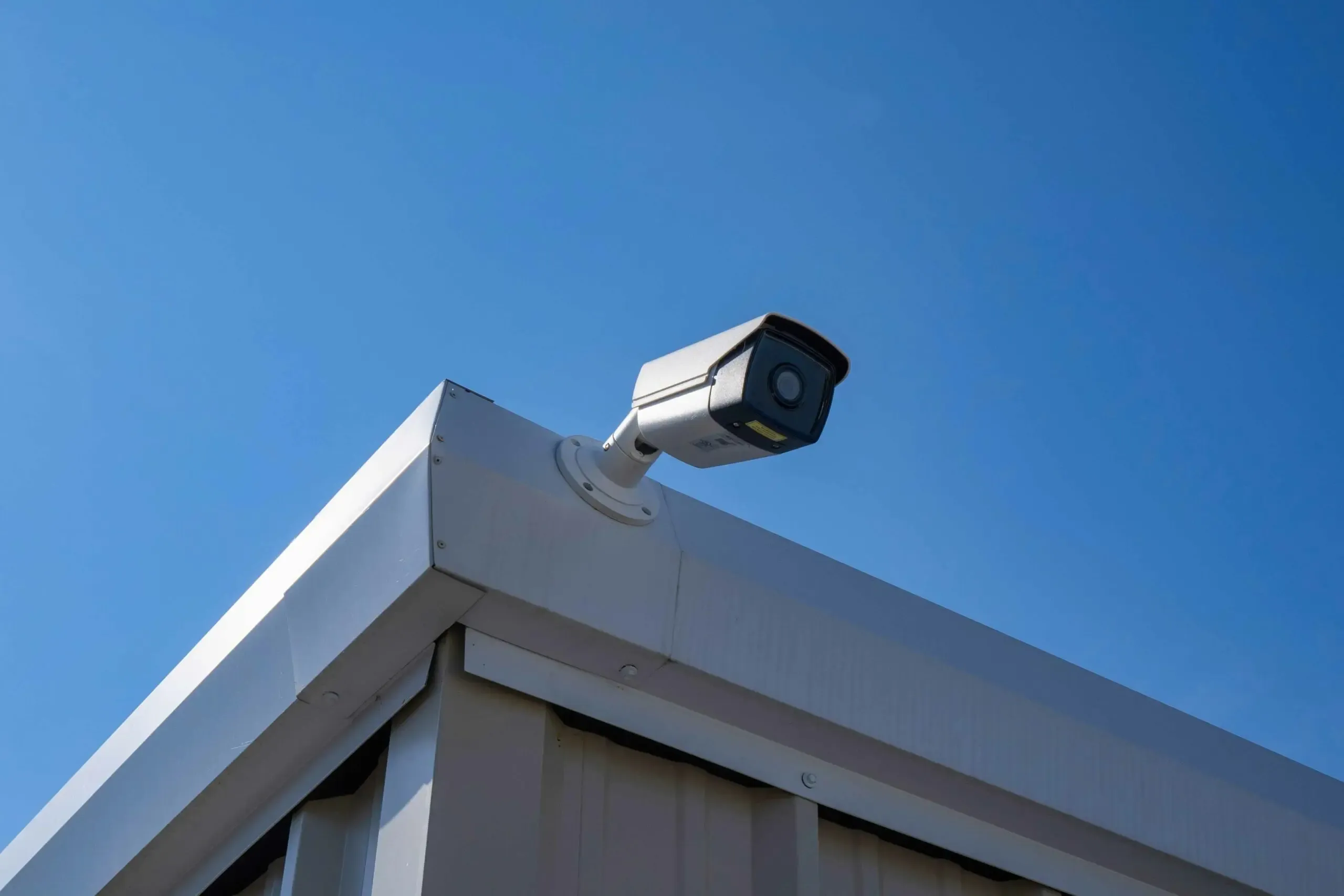A security camera on the edge of a unit building.